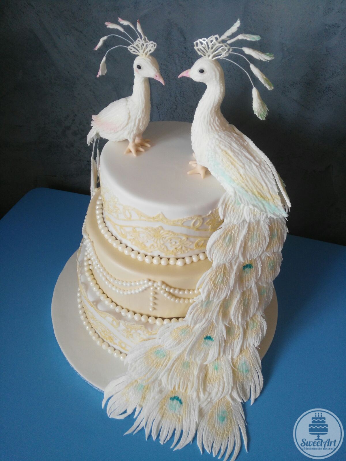 O bijuterie de tort de nuntă cu păuni, dantelă și mărgele