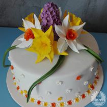 Tort cu flori de primăvară: narcise albe și galbene și liliac mov, floricele și frunze