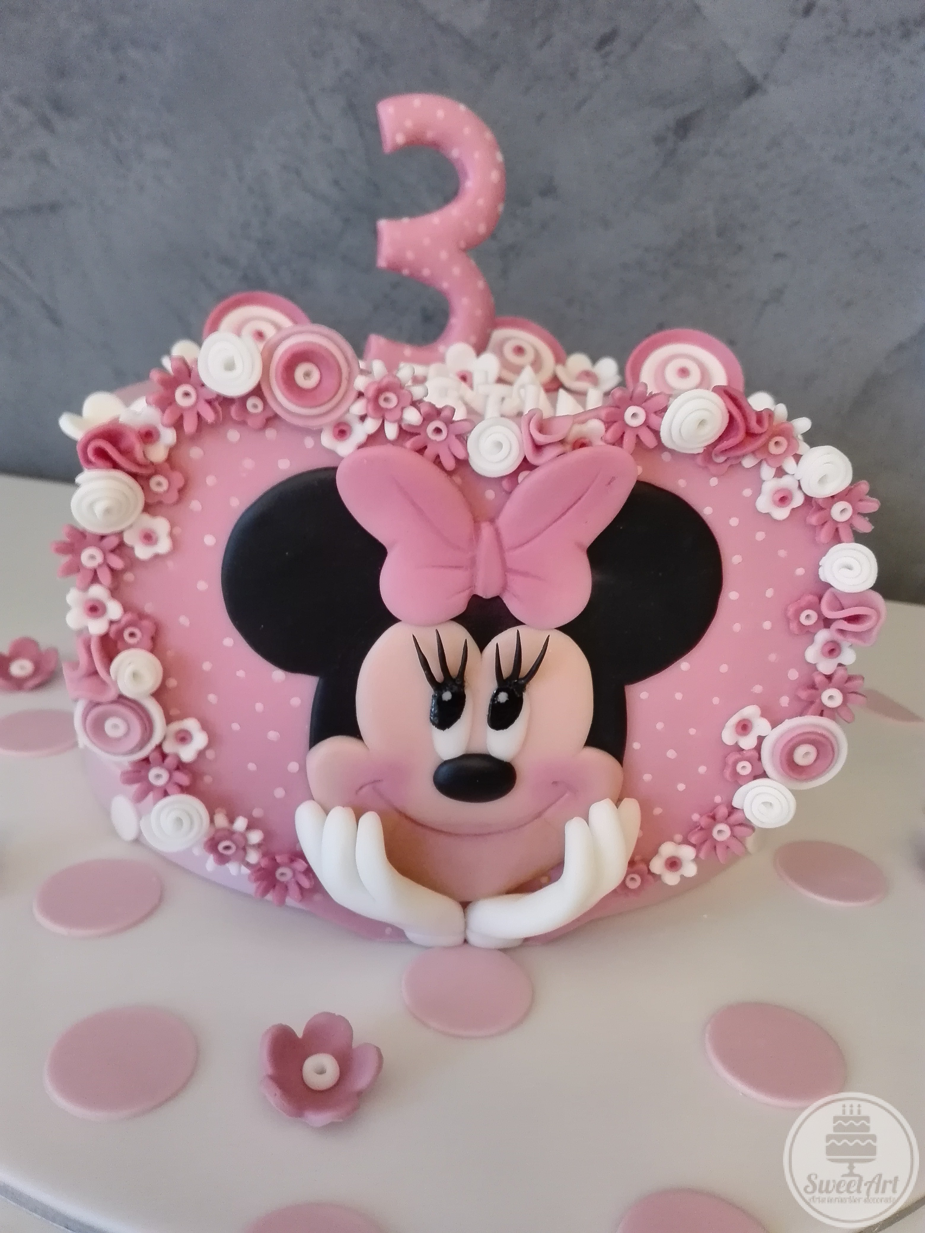 Tort inimă mare roz cu Șoricica Minnie – Minnie Mouse 2D, buline mici albe și multe, multe floricele albe și roz, tort alb cu buline roz și flori