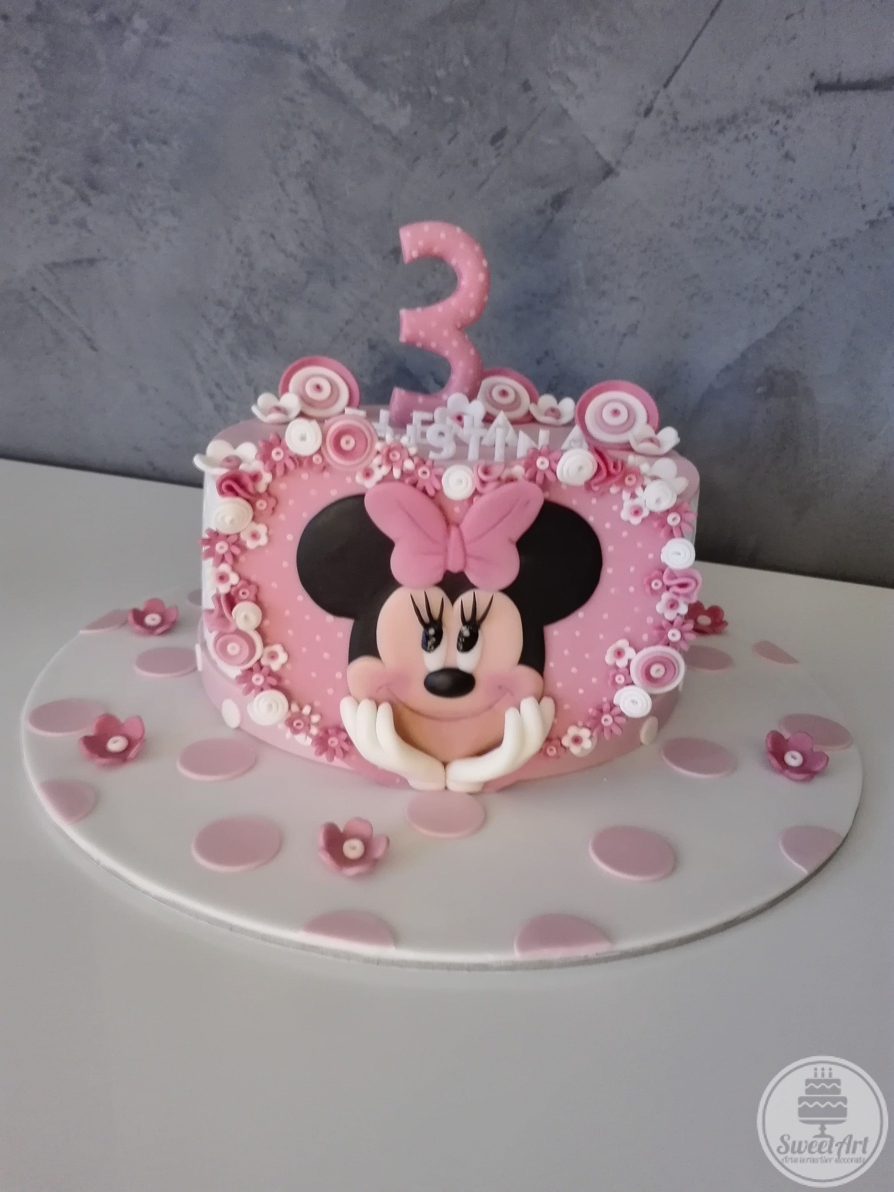 Tort inimă mare roz cu Șoricica Minnie – Minnie Mouse 2D, buline mici albe și multe, multe floricele albe și roz, tort alb cu buline roz și flori