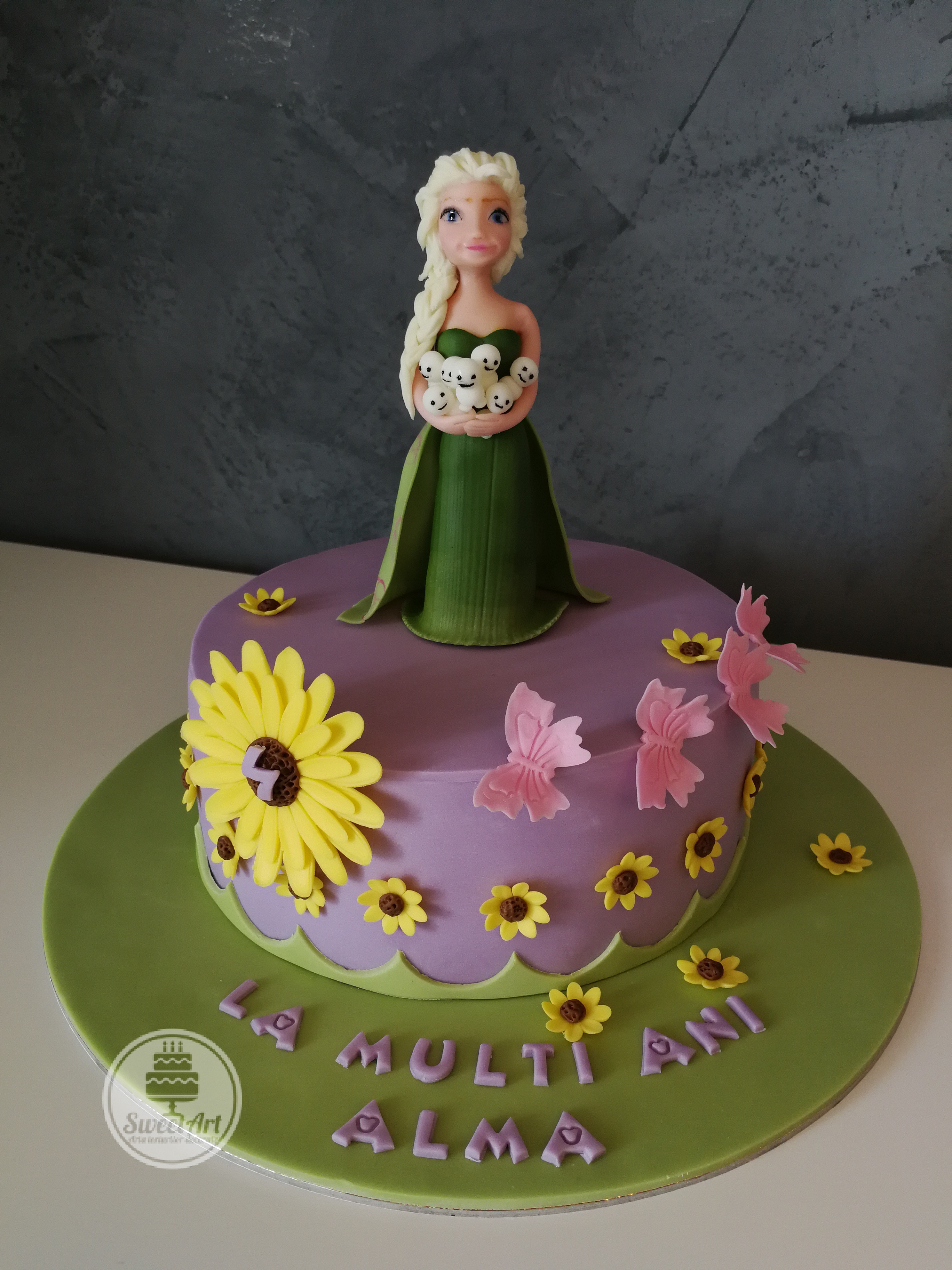 Tort Elsa - Febra Regatului de gheață - Frozen Fever: Elsa în rochie verde smarald cu omuleți de zăpadă în brațe, flori și floricele de floarea soarelui, floricele galbene, fluturași roz, tort mov cu verde