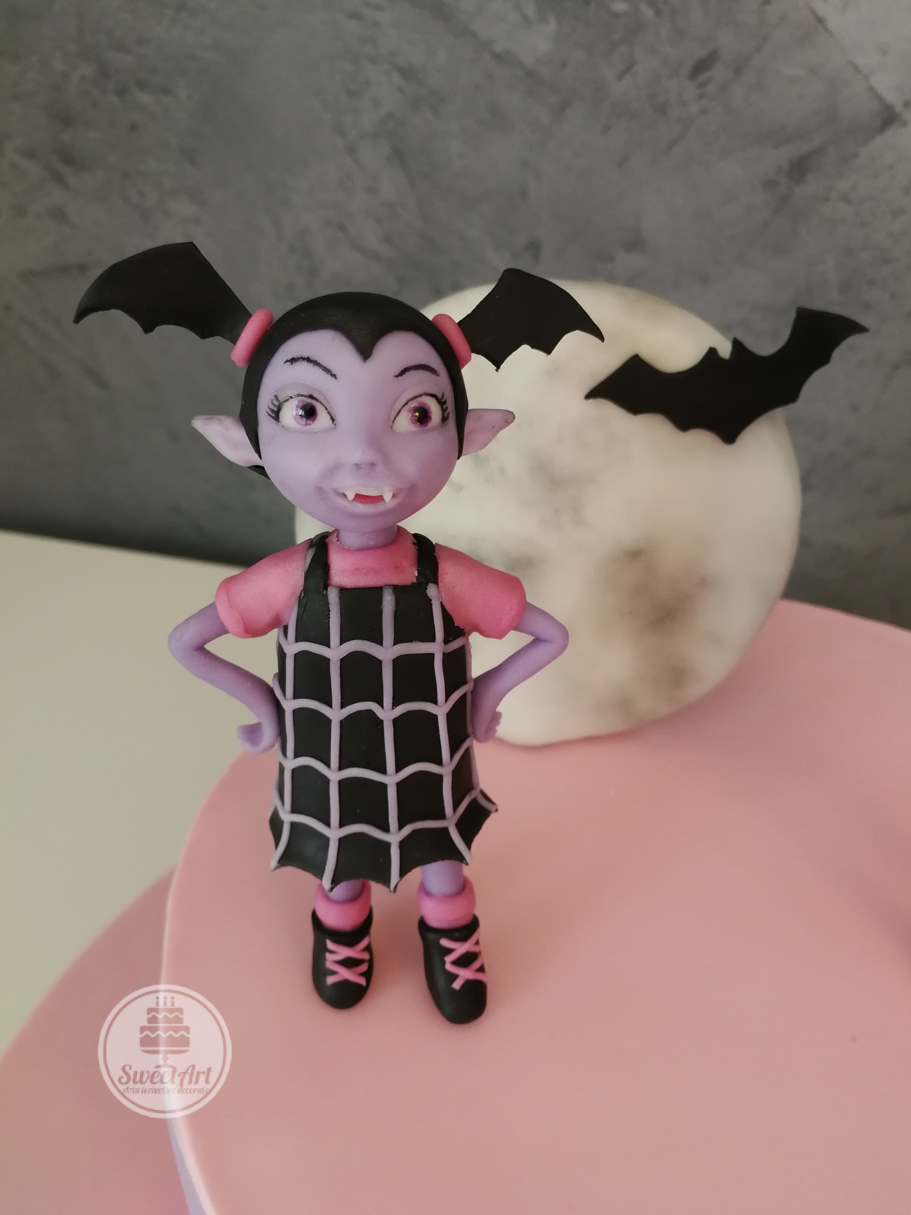 Vampirina, o fetiță vampir cu o rochiță cu pânză de păianjen și codițe aripi de liliac lună plină, liliac, tort mov cu roz