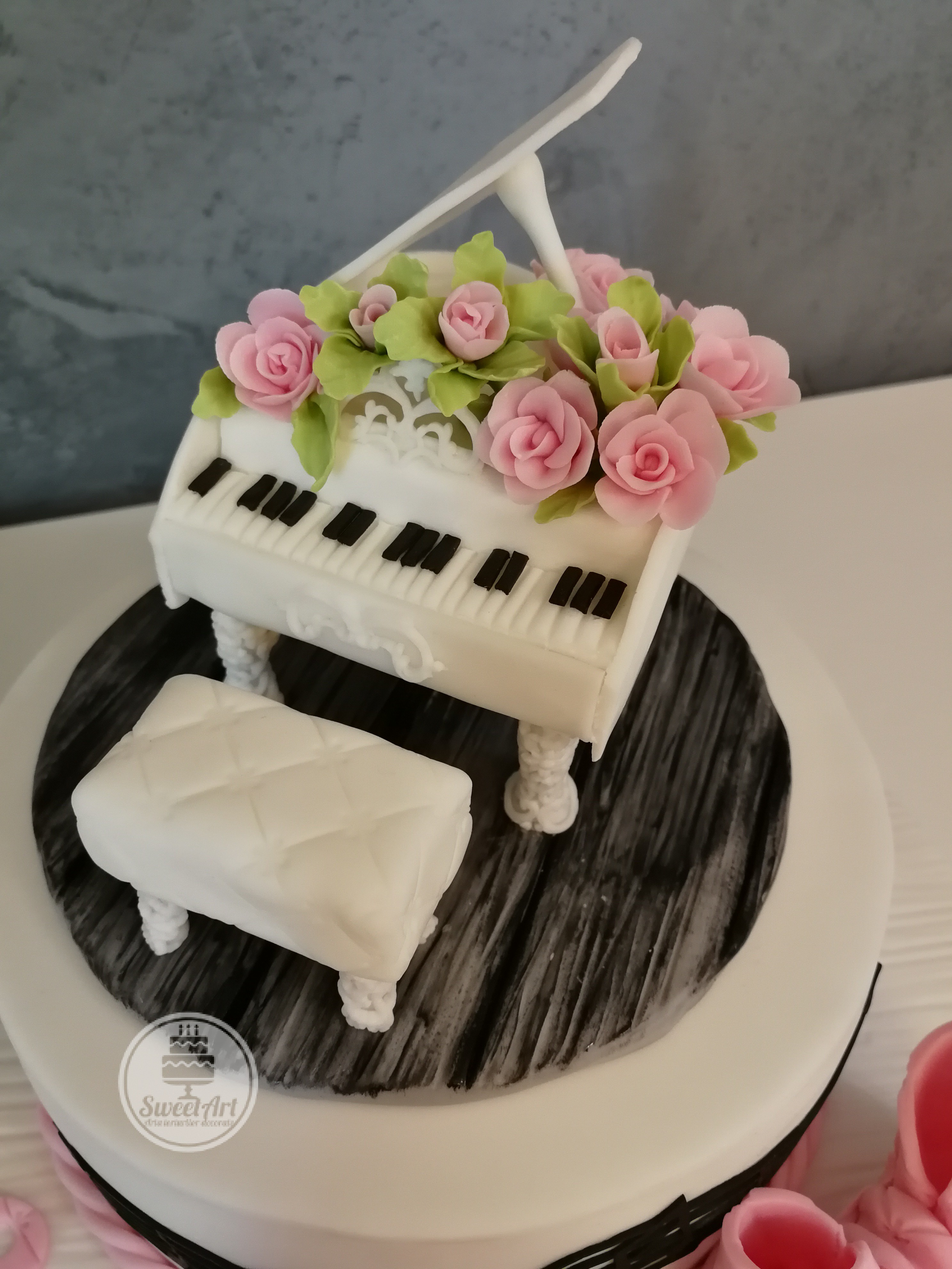 Pian cu aranjament cu trandafiri roz și frunze și banchetă albă pian pe parchet lemn negru, lemn alb, tort alb