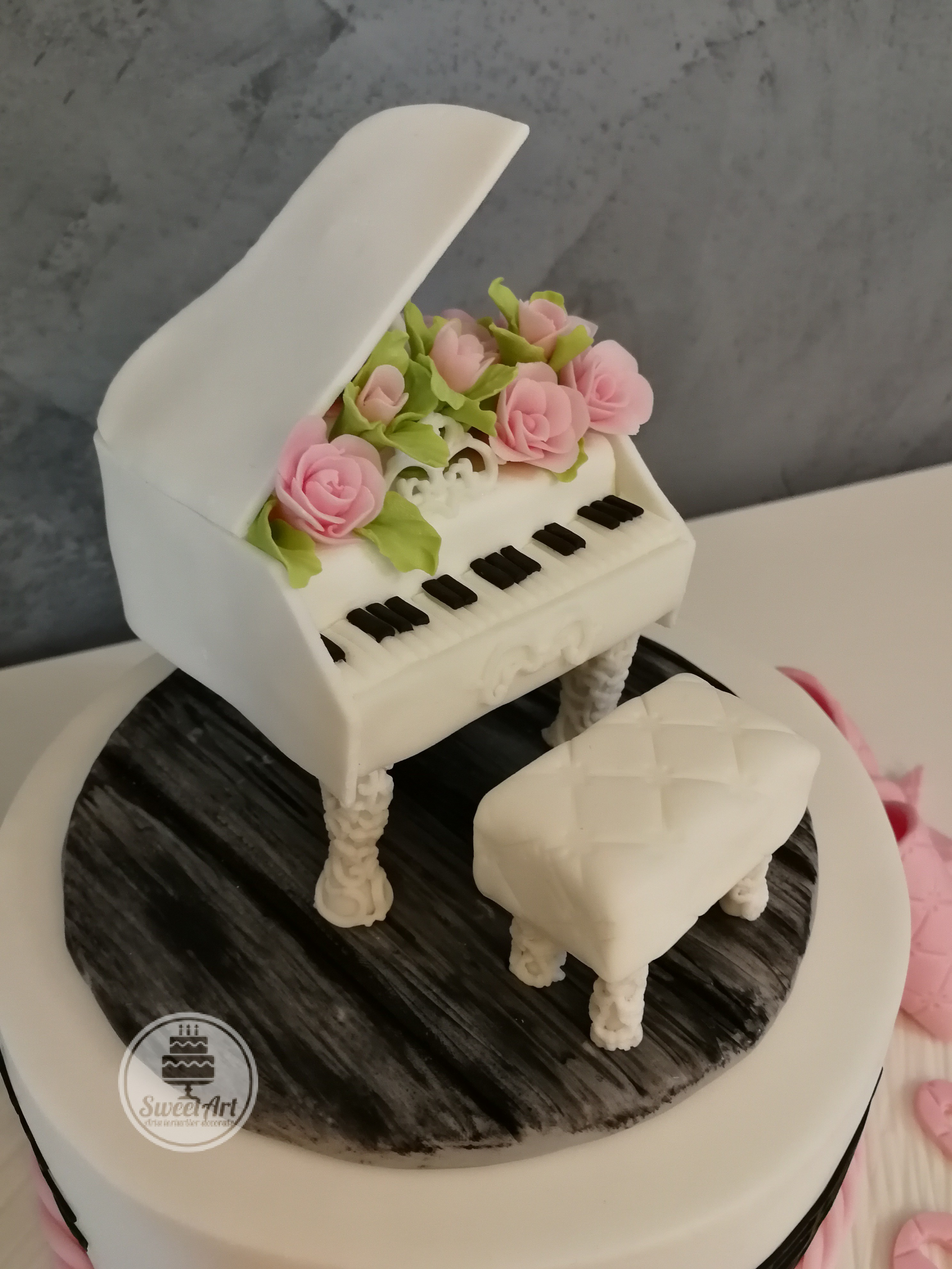 Pian cu aranjament cu trandafiri roz și frunze și banchetă albă pian pe parchet lemn negru, lemn alb, tort alb