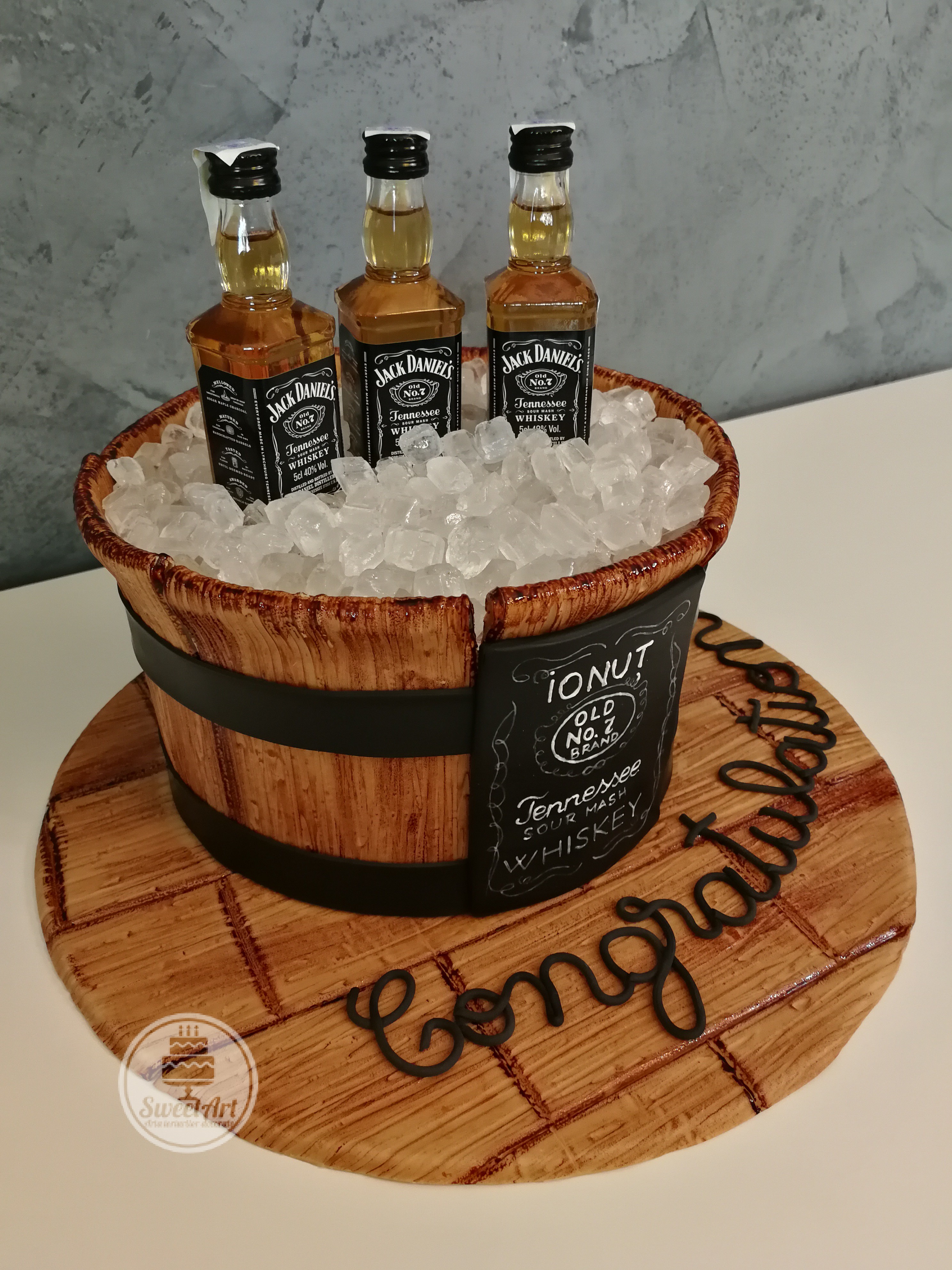 Un alt tort frapieră de lemn cu gheață din zahăr și whiskey Jack Daniel's pe platou de lemn și etichetă pictată manual